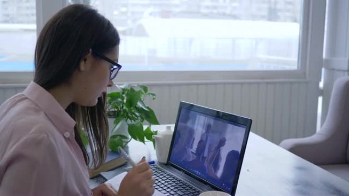 在线课程，戴眼镜的学生女性正在学习以实现自我发展。在培训中使用现代技术并在笔记本上做笔记
