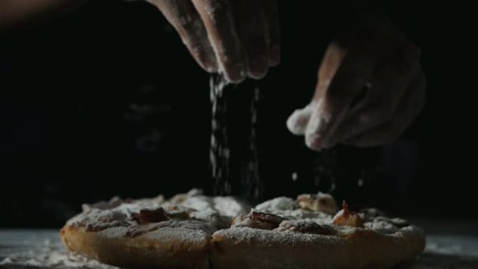 女人用手在慢动作的比萨饼上撒上面粉
