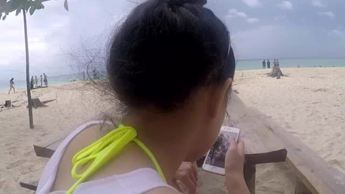 亚洲妇女在海滩上使用智能手机