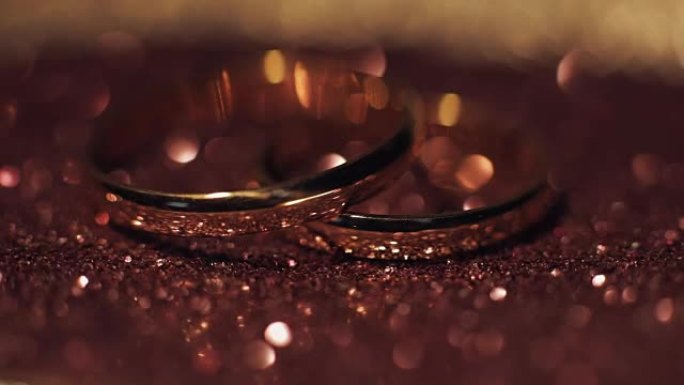 结婚戒指躺在闪亮的表面上，闪耀着光亮的特写微距