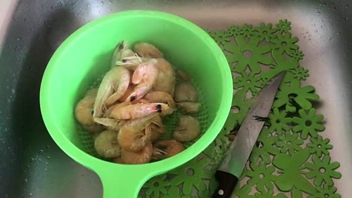 煮熟的虾躺在漏勺里。蒸汽来自他们。