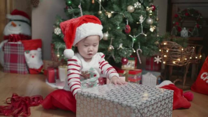 女婴在家里的圣诞树前打开礼品盒