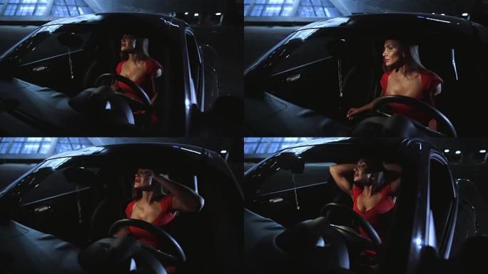 性感的女人与大胸部在红色连衣裙坐在汽车沙龙看后视镜