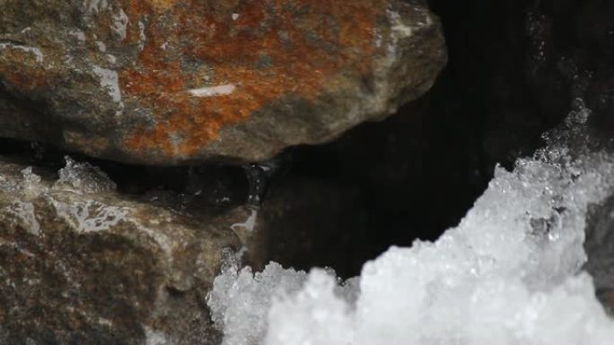 融化天然石头上的雪。瀑布，冰，水。你好，春天。选择性聚焦。