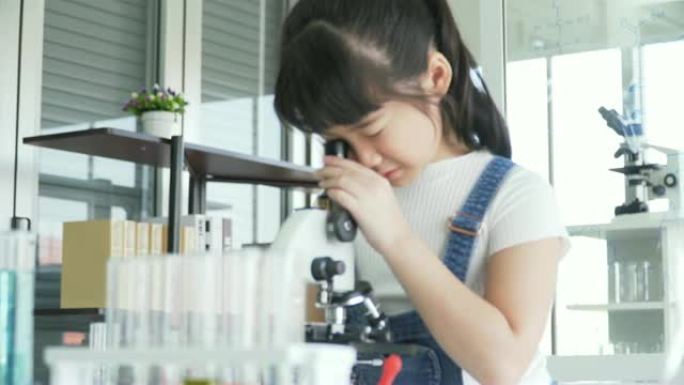 dolly拍摄的侧视图: 好奇的亚洲女孩根据自己的意愿调整光学显微镜