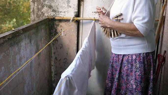 老妇人从她的旧阳台线上洗好的悬挂衣服，特写