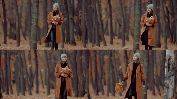 秋天森林里的女孩，一束橙色的叶子