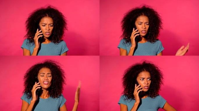愤怒的非洲裔美国妇女，卷发，穿着绿色t恤，在粉红色的墙壁背景上用智能手机打电话。女孩紧张，表达不满和