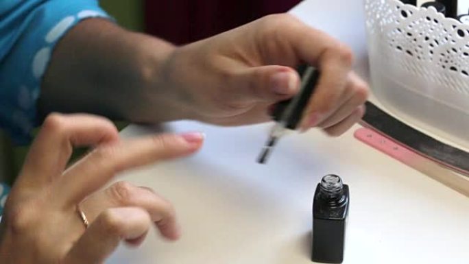 一个女人修指甲。用刷子在指甲上刷凝胶。