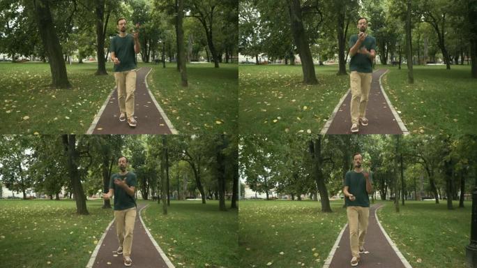 男子杂耍演员走在格子呢跑道上，展示了与球，万向节射击，公园树木的杂耍。