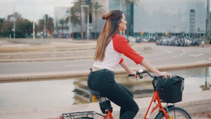 年轻女子或女孩骑自行车在棕榈树旁踩踏板