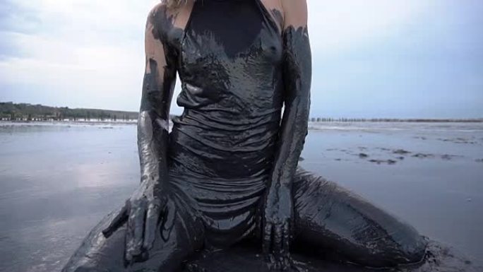 坐在那里的性感女人沾上了黑泥，看起来像石油