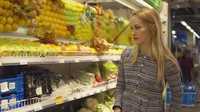 超市里的漂亮女孩在超市里挑选蔬菜和水果。