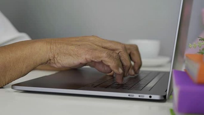 老女手在笔记本电脑键盘上打字