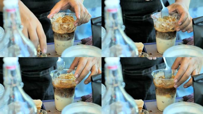 专业咖啡师将咖啡倒入加冰的玻璃杯中，并在繁忙的咖啡店中添加牛奶。视频慢动作