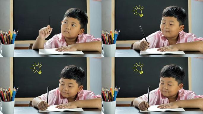 可爱的亚洲小男孩在写书时头顶上有一个明亮的想法灯泡。创新、想象力和鼓舞人心的想法的概念