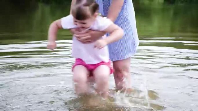 小女孩的母亲在河里洗脚。女人在海滩上玩她的孩子