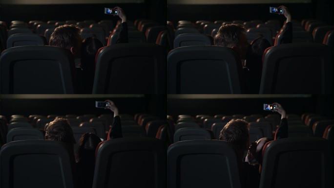 年轻人在空荡荡的电影院里接吻。情侣自拍照片