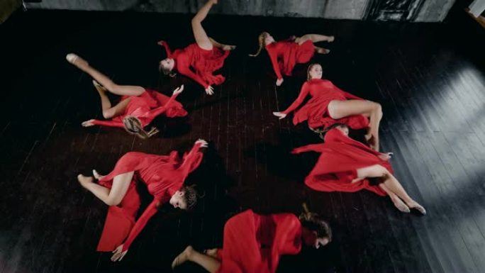 七名女舞者圆圆的躺在地板上，移动并站起来，俯视图在他们的身体上