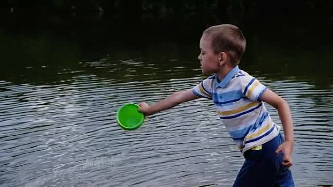 小男孩愤怒地把水桶里的水倒进河里。儿童在大自然中玩耍