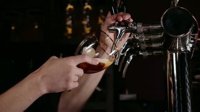 调酒师的手在餐厅或酒吧的水龙头中倒入大啤酒