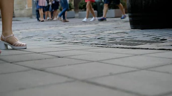 穿鞋的人的脚走在石头路上。在城市里散步。