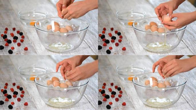 女人的手打碎鸡蛋以分离蛋清，蛋黄和蛋壳的背景。