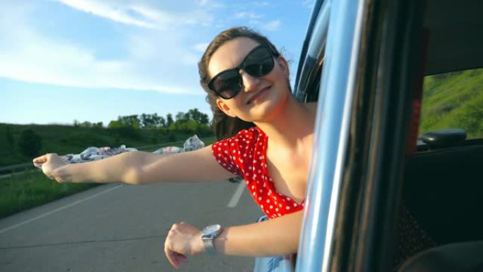 戴着墨镜的年轻女孩，手里拿着围巾，斜靠窗外的复古汽车，为旅行感到高兴。迷人的女人微笑着，喜欢在阳光明