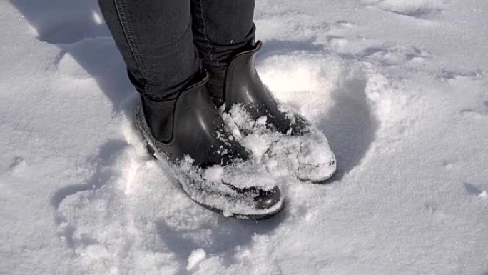 一个年轻女孩在雪地里的腿。那个女人在一个冰雪覆盖的冬季公园里冻僵了。