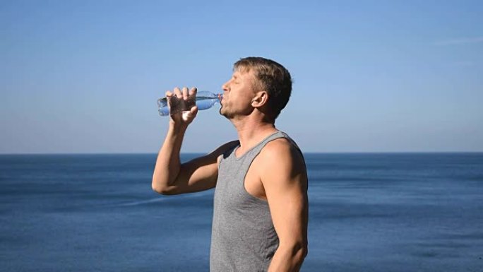 一名男子从海洋上的塑料瓶中喝水，运动后止渴