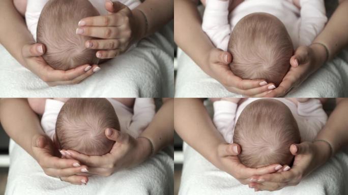 母亲的双手握住新生婴儿的小头