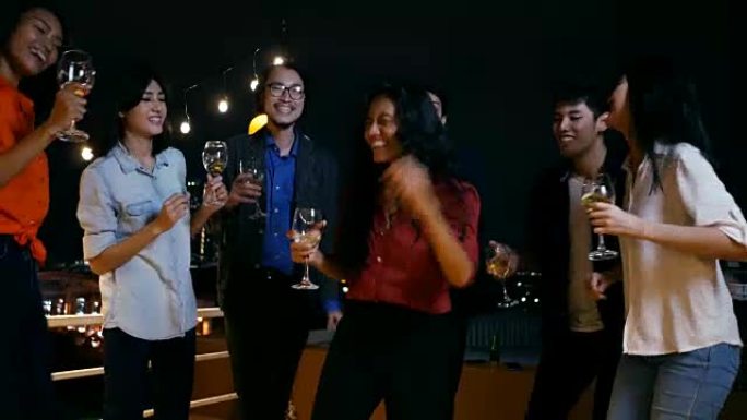 亚洲人民和朋友在屋顶晚会上喝啤酒和跳舞。4k分辨率。