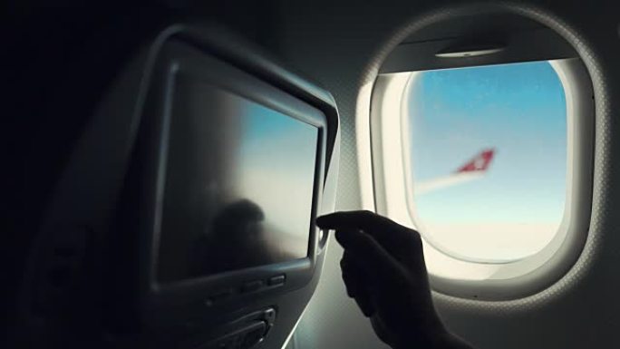 男性乘客在机场机舱座位上触摸显示器，手的特写镜头