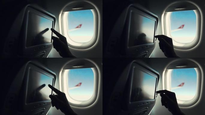 男性乘客在机场机舱座位上触摸显示器，手的特写镜头