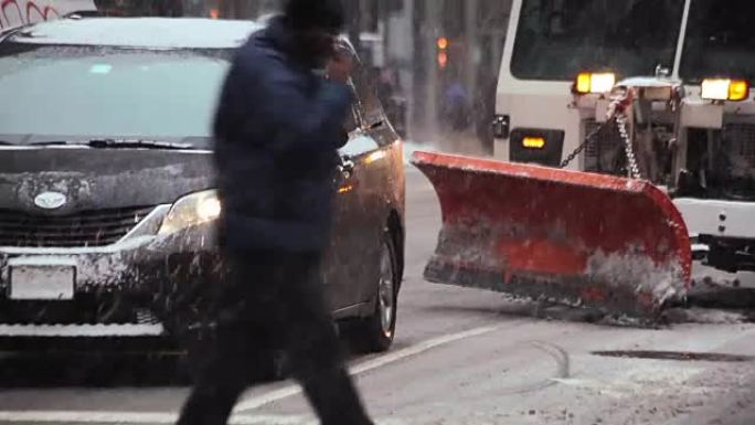一名骑自行车的人在暴风雪中穿过纽约市列克星敦大街的一个十字路口缓慢地驶过扫雪机