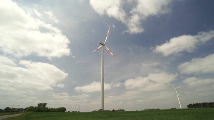 风力涡轮机和电力线，绿色的草地和带有大云的蓝天