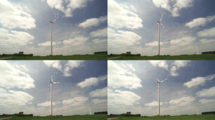 风力涡轮机和电力线，绿色的草地和带有大云的蓝天
