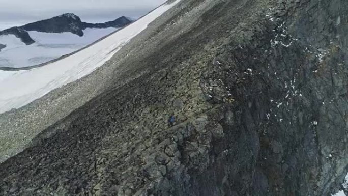 徒步旅行者正在悬崖附近的挪威雪山徒步旅行和攀登。鸟瞰图