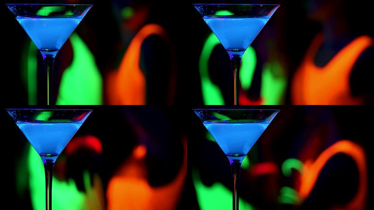 蓝色发光饮料与跳舞的女人在紫外线发光派对背景。。