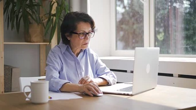 成熟的女商人正在使用坐在家庭办公空间的笔记本电脑