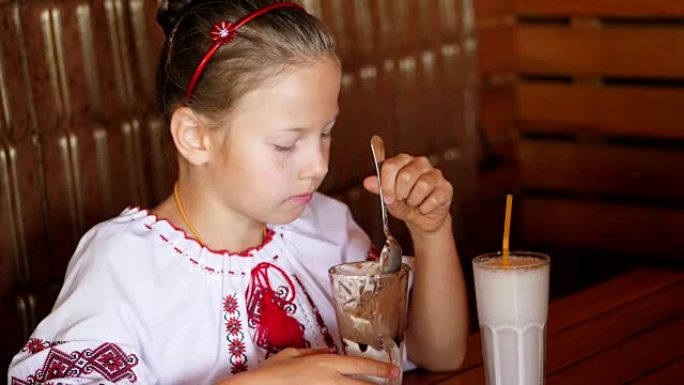 快乐微笑的少女，孩子在咖啡馆吃冰淇淋。她穿着乌克兰民族服装，刺绣，维希万卡