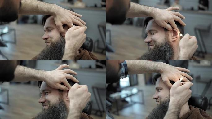 理发师在男士发廊中与留着长胡子的成年男子一起用火。梳理胡须。工作场所的理发师。理发店的胡须发型设计和