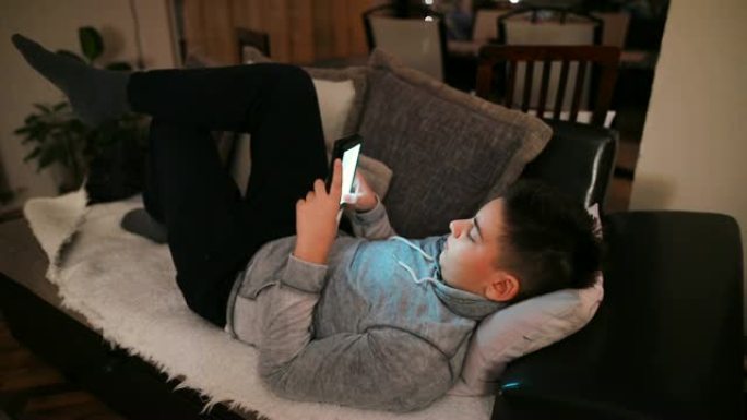 青少年与躺在沙发上的智能手机上的朋友聊天，社交网络