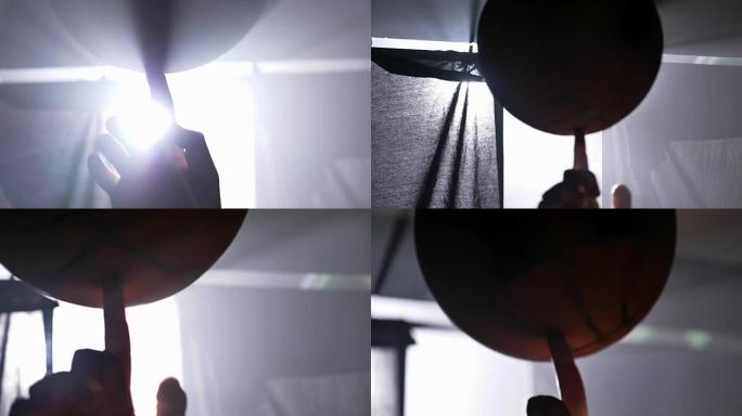 篮球运动员手指上旋转的球的近距离镜头，带泛光灯的黑暗迷雾房