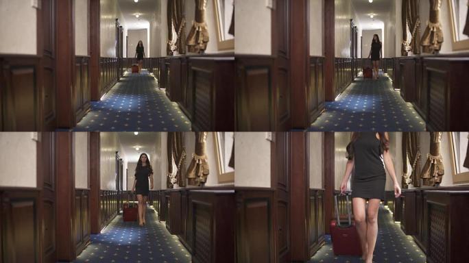 一张空荡荡的酒店走廊的照片。一个带着拉杆箱的黑发女人正从楼梯进入走廊，沿着走廊看着侧面。