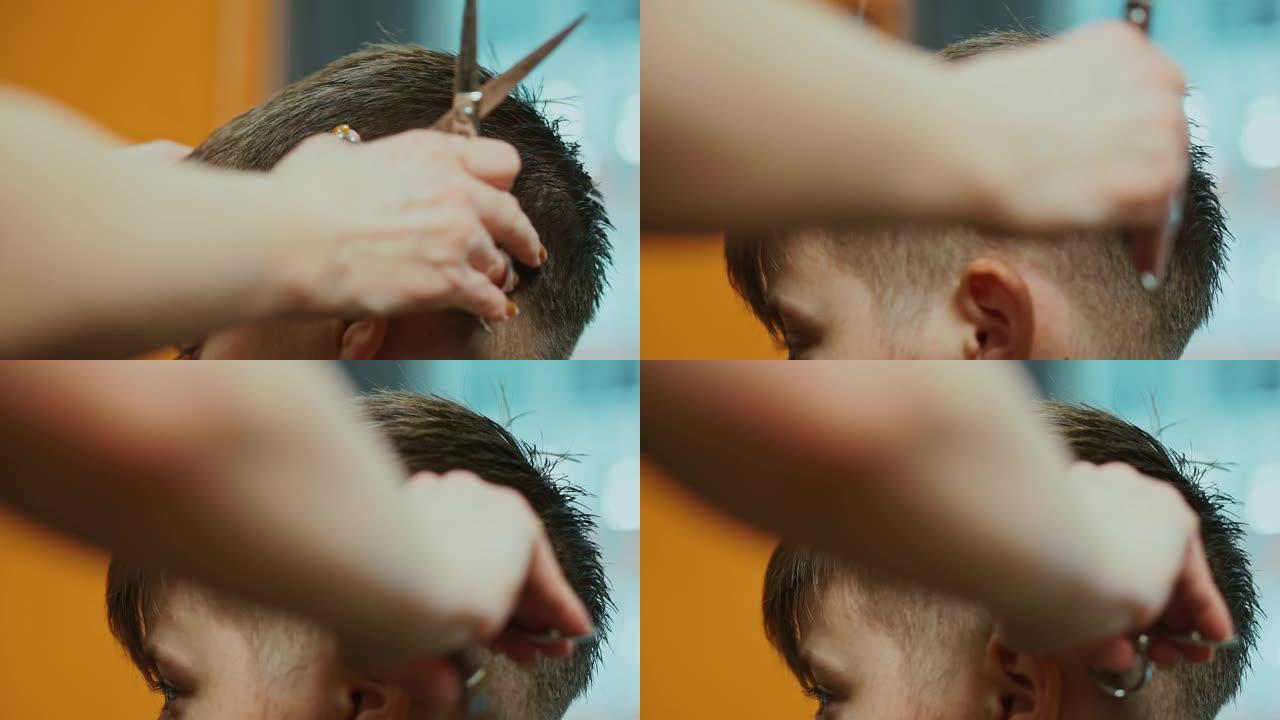 在美发沙龙剪掉男孩头发的理发师的手。