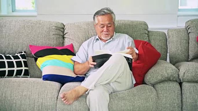 老人在客厅看书。白胡子的亚洲老人。高级生活方式概念。滑块镜头。