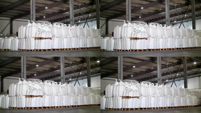 库存的大袋谷物产品。袋子成排堆叠，工业仓库