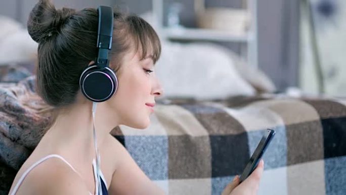 女性音乐爱好者使用智能手机在耳机中收听和享受喜爱的曲目