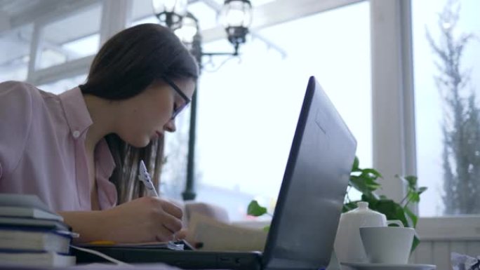 学习过度劳累，疲倦的学生妇女眼镜使用笔记本电脑在远程教育期间从在线教学中准备考试，并用手遮住脸